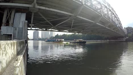 Schlepper-Boot-schleppen-Lastkähne-am-Pasig-River-in-Richtung-lange-Span-Eisenbrücke.