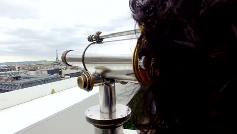 Tourist-woman-enjoy-Paris-cityscape-view-with-coin-binocular-telescope-at-top-terace-balcony-in-Galery-Lafayette