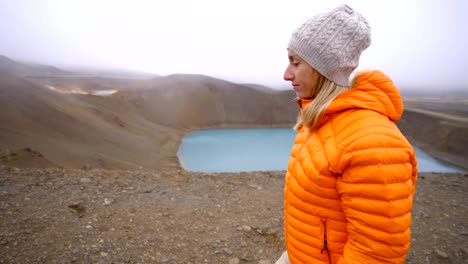 Young-woman-in-Iceland-contemplating-crater-lake-from-top-of-it,-Springtime.-People-travel-carefree-lifestyles-concept--4K-video