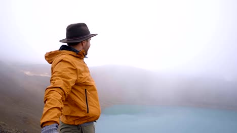 Young-man-arms-outstretched-at-spectacular-crater-lake-in-Iceland