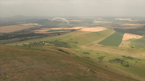 Athlet-Gleitschirm-fliegt-auf-seinem-Gleitschirm-neben-die-Schwalben.-Follow-up-Aufnahmen-aus-der-Drohne