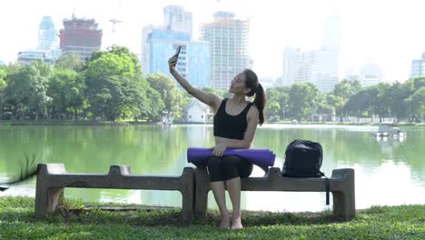 Mujer-sentada-en-el-parque-y-mediante-teléfono-móvil