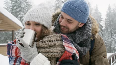 Schönes-Paar-umarmt-und-Teetrinken-im-Winterwald