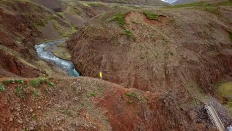 Amazing-drone-point-of-view-of-woman-hiking-on-mountain-ridge-over-canyon-in-Iceland.