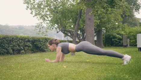 Tablón-de-formación-fitness-mujer-ejercer-sobre-hierba-en-el-parque-de-verano