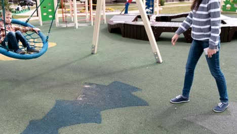 Mom-swing-son-on-empty-webbed-swing.