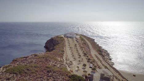 Aerial-view-of-a-dirt-road-with-a-big-house-at-the-end-and-the-sea-around.