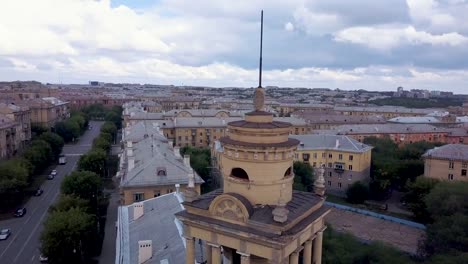 Drone-en-vuelo-cerca-de-la-torre-de-estilo-antiguo-con-fábrica-en-el-fondo