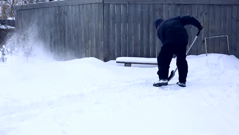 Trabajar-después-de-noche-de-nieve.-Hombre-con-una-pala-quitando-la-nieve-de-su-jardín-en-una-fría-mañana-de-nieve