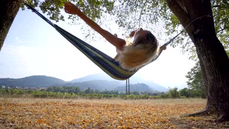 Mujer-joven-alegre-en-hamaca-relajante-en-otoño---personas-viajar-concepto-de-vacaciones-naturaleza