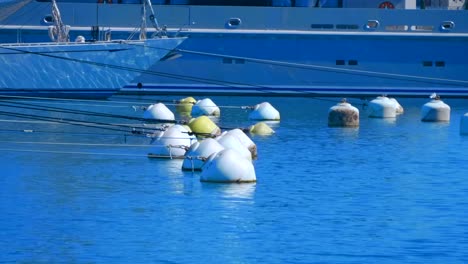 Reihen-aus-weißen-Schlachtzugsfässern-sind-durch-Seile-mit-Schiffen-und-großen-Yachten-verbunden