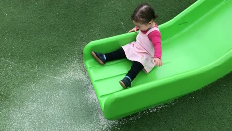 Little-girl-sliding-on-a-slide-in-the-playground