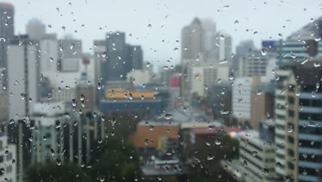 Caídas-de-gotas-de-lluvia-en-una-ventana-con-vistas-al-paisaje-urbano