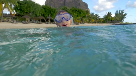 Slow-motion-view-of-small-boy-swimming-in-the-Indian-Ocean-in-the-snorkeling-mask-and-take-a-picture,-Port-Louis,-Mauritius-Island