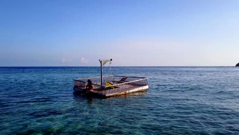 v03834-vuelo-drone-vista-aérea-de-Maldivas-playa-2-personas-pareja-hombre-mujer-relajante-en-la-isla-de-paraíso-tropical-soleado-con-cielo-azul-aqua-agua-mar-4k-flotante-pontoon-embarcadero-el-sol-juntos