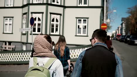 Back-view-of-young-stylish-couple-walking-in-downtown-together.-Man-and-woman-holding-hands-and-exploring-the-city