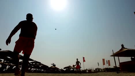 Silueta-de-dos-hombres-jugando-al-tenis-playa-en-la-playa