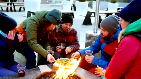 Freunde,-die-Snacks-in-der-Nähe-von-Lagerfeuer