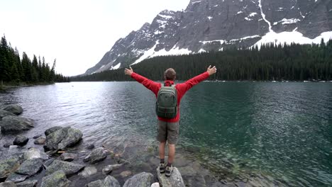 Hiker-celebrating-by-mountain-lake,-4K