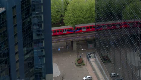 Straßenbahn-zwischen-Gebäuden,-Dlr-Zug,-finanzielle-Ticker,-Canary-Wharf,-London