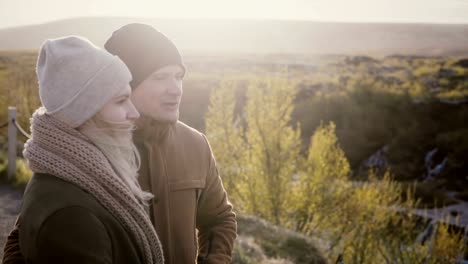 Young-beautiful-couple-standing-in-sunny-valley-and-talking,-enjoying-the-beautiful-view-in-Iceland