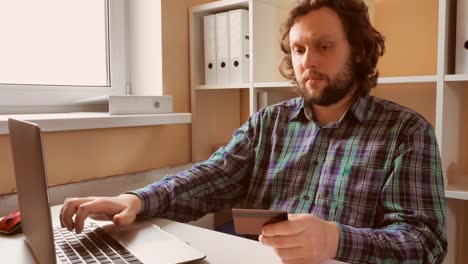 handsome-male-sitting-at-the-desk-shopping-online