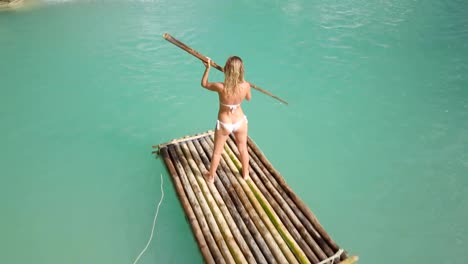 Drone-shot-aerial-view-of-young-woman-bamboo-rafting-at-tropical-waterfall.-4K-resolution-video,-shot-in-the-Philippines.-People-travel-fun-vacations-adventure-concept