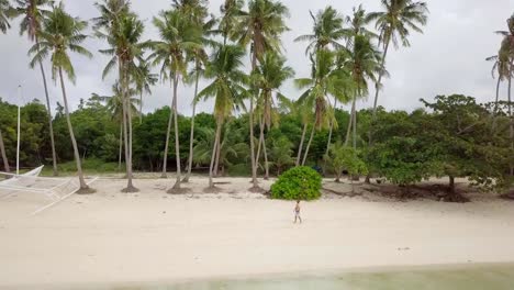 Drone-shot-aerial-view-of-young-man-relaxing-on-tropical-beach,-contemplating-nature.-4K-resolution-video.-People-travel-vacations-concept.-Shot-in-the-Philippines,-Asia