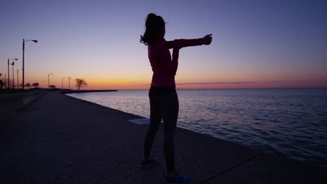 Hispanic-Caucasian-female-silhouette-stretching-in-Chicago-sunset