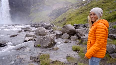 Follow-me-to-the-waterfall-young-woman-waving-at-boyfriend,-girlfriend-leading-man-to-falls-in-Iceland-People-travel-concept--Slow-motion