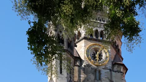 Reloj-de-la-Iglesia-Memorial-Kaiser-Wilhelm-detrás-de-un-árbol-en-Berlín,-Alemania