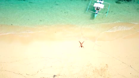 Drone-shot-aerial-view-of-young-woman-lying-down-like-star-shape-on-idyllic-tropical-beach-,-shot-in-the-Philippines