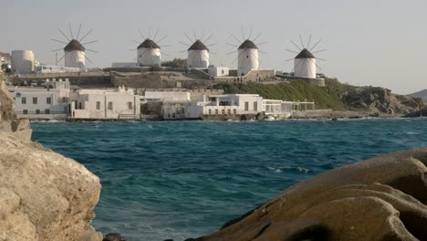 die-berühmten-Windmühlen-auf-Mykonos,-umrahmt-von-einer-Felsenküste