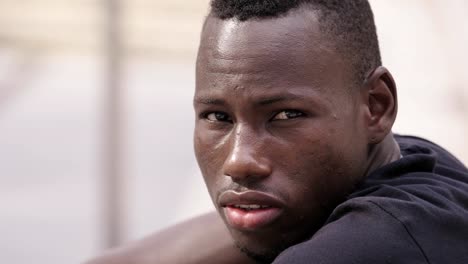 close-up-portarit-of-young-serious-black-american-man-turning-and-looking-at-camera--outdoor