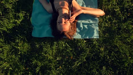 Attractive-sexy-handsome-red-hair-young-woman-lying-on-grass-and-calling-on-mobile-phone