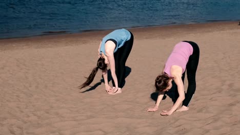 Zwei-Frau-Yoga-am-Strand-am-Fluss-in-der-Stadt-zu-tun.-Schöne-Aussicht.