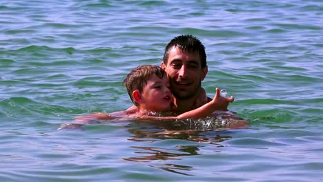 Joven-padre-con-un-hijo-pequeño-en-la-playa-de-la-mar,-Grecia