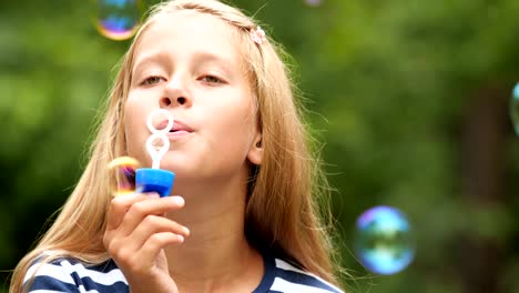 Little-girl-playing-with-soap-bubbles-outdoor.-Slow-motion.