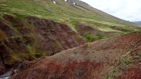 Amazing-drone-point-of-view-of-man-hiking-on-mountain-ridge-over-canyon-in-Iceland