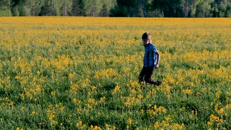 Niño-corre-en-el-campo-entre-las-flores-amarillas.