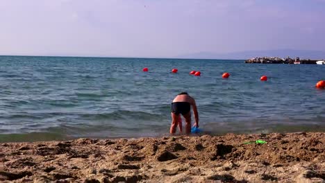 Kleiner-Junge-am-Meeresstrand-im-Sand-spielen