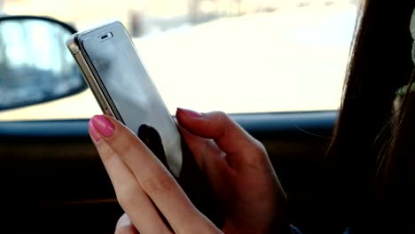 Close-up-Frauenhand-messaging-ihr-Handy-im-Auto-zu-sitzen.-Seitenansicht.