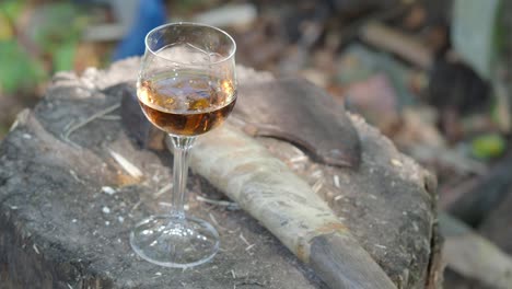 glass-of-cognac-and-an-ax-on-a-wooden-deck