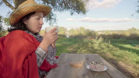 Mujer-joven-en-un-sombrero-de-paja-tomando-té