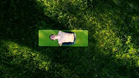 Slender-young-man-practicing-yoga-in-park.-Top-view.-Copter-footage.