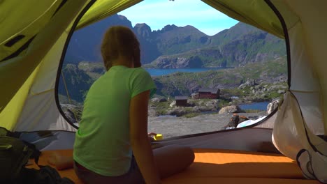 A-girl-sits-in-a-tent-and-looks-at-the-beautiful-nature-of-Norway