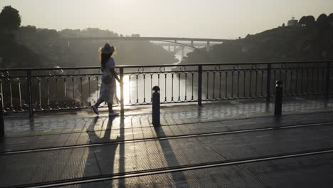 Lady-in-hat-and-dress-walking-on-bridge