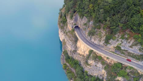 Carretera-de-montaña-con-lago-azul-abajo-y-túnel