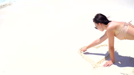 Junge-Frau-am-Strand-auf-dem-weißen-Sand-zeichnen