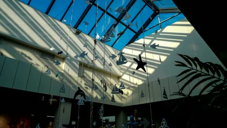 Glass-ceiling-of-the-shopping-center-with-paper-garlands-on-a-background-of-time-lapse-light-of-the-sun-rays-on-a-blue-sky